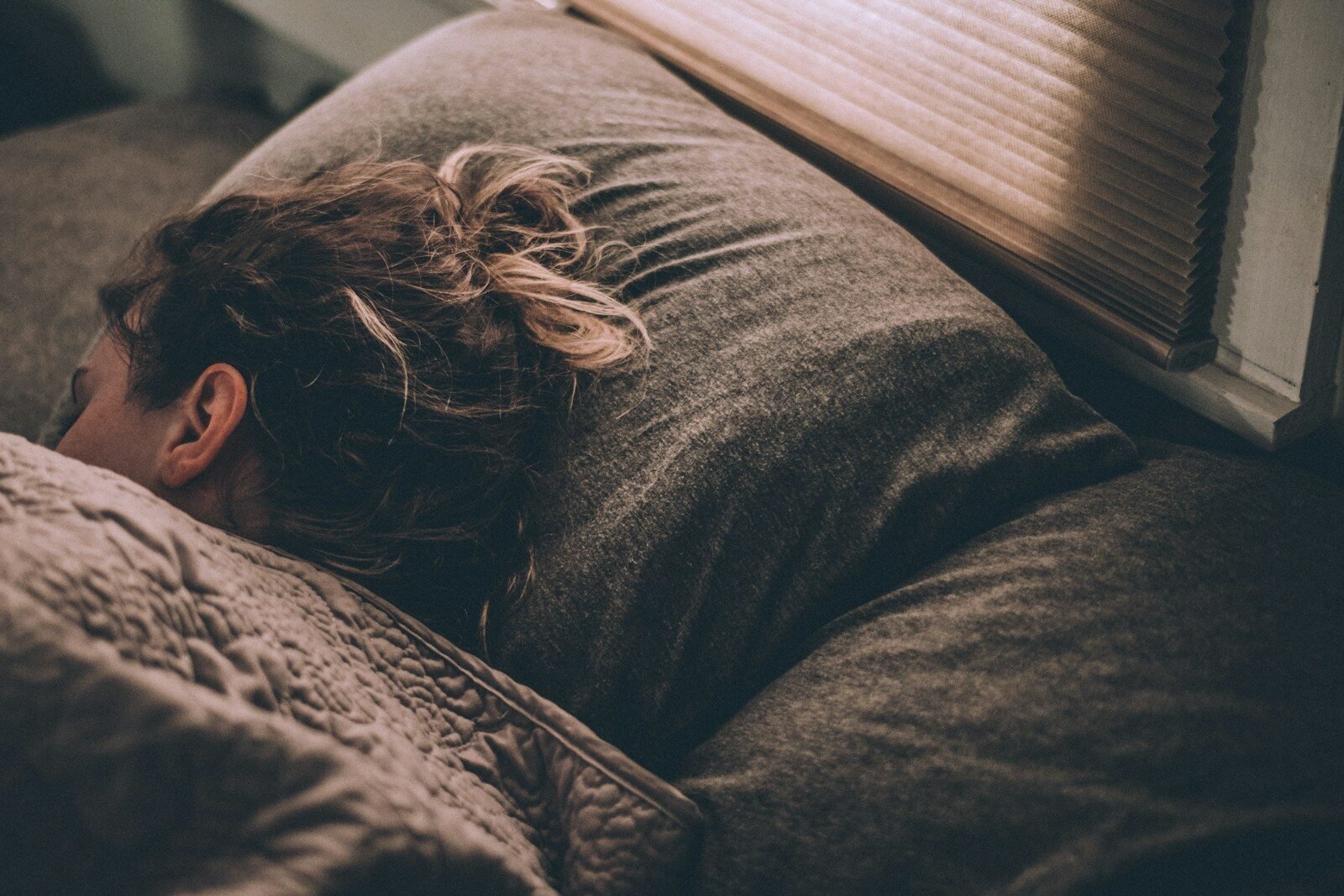 Woman sleeping peacefully in bed under blankets